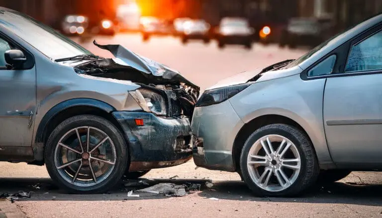 two cars after a car accident, both front ends damaged on a busy road