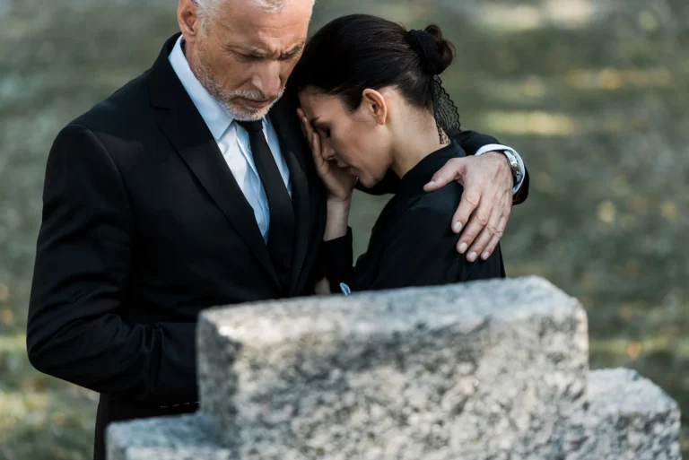 Man hugging upset woman an funeral
