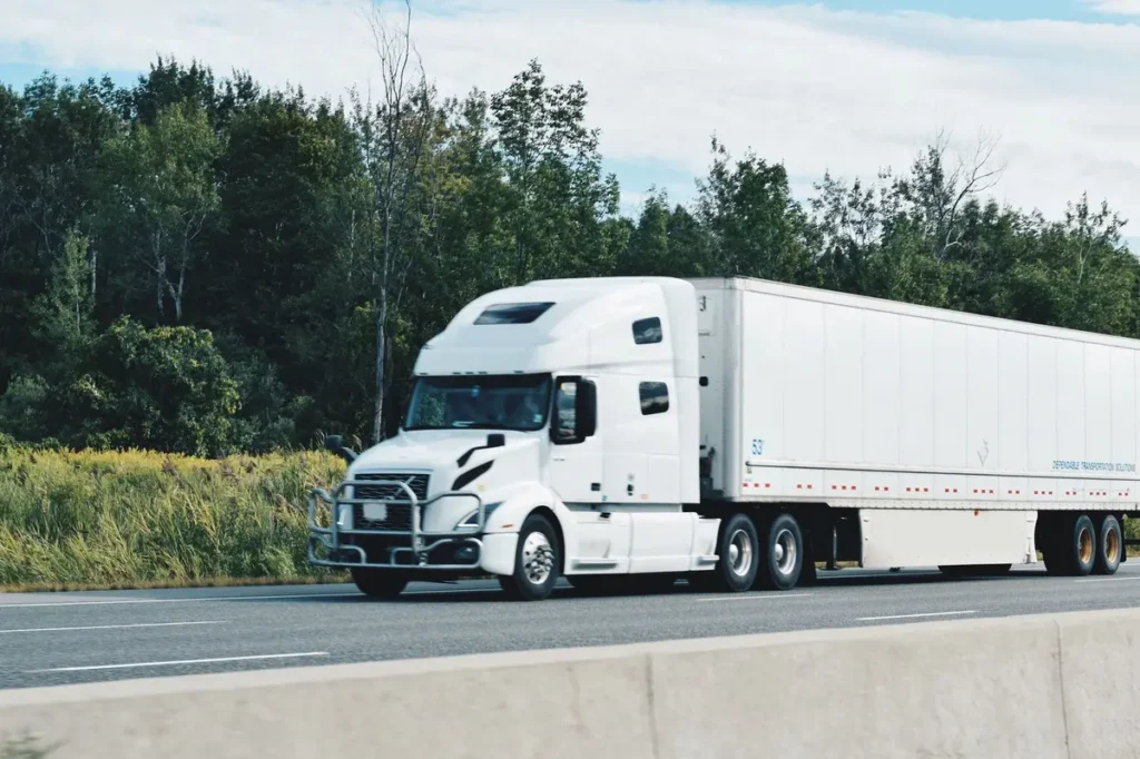 Truck Accidents - Franklin Law, LLC. All white 18-wheeler tractor trailer driving on a highway transporting and delivering goods and shipments