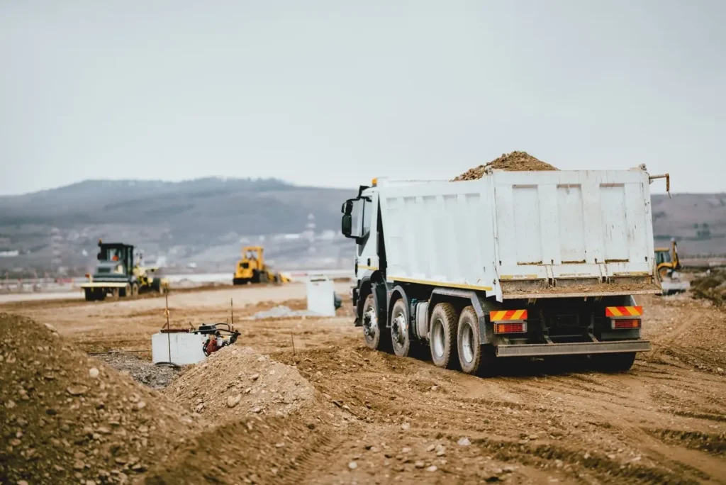 Truck Accidents - Franklin Law, LLC. Industrial dumper trucks working on highway construction site. construction truck accident lawyer concept.