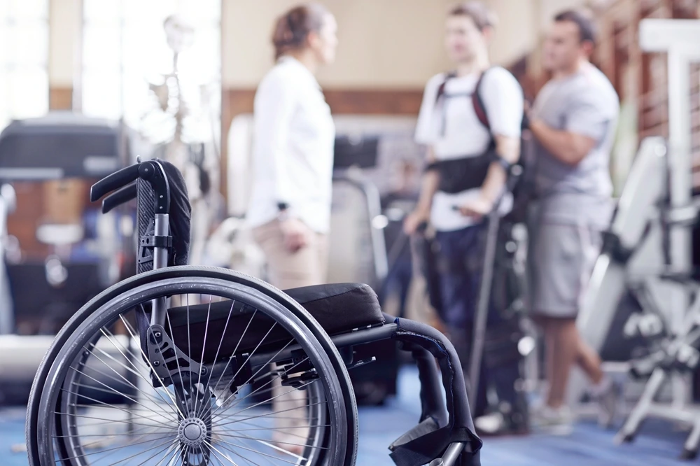 Man receiving physical therapy with wheelchair in foreground. spinal cord injuries and paralysis.